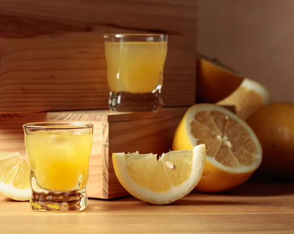 伝統的な自家製レモンリキュールリモンチェッロと木のテーブルの上に新鮮な柑橘類 — ストック写真