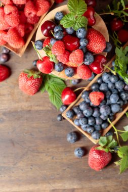 Various fresh berries on a wooden table. Strawberries, blueberries, raspberries, and cherries are presented. Top view.