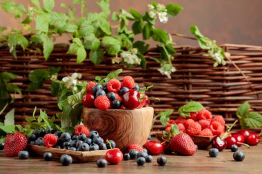 Various fresh berries on a wooden table. Strawberries, blueberries, raspberries, and cherries are presented.