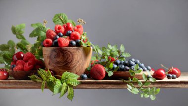 Various fresh berries on a wooden table. Strawberries, blueberries, raspberries, and cherries are presented.