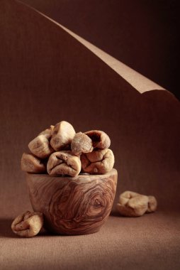 Kahverengi arka planda eski bir ahşap kapta kurumuş incir. Boşluğu kopyala.