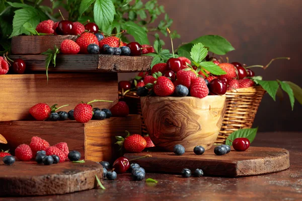 Yapraklı taze böğürtlen. Eski bir masada çilek, ahududu, yabanmersini ve tatlı kirazlar.. 