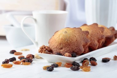 Mutfak masasında fındıklı ve kuru üzümlü kekler. Beyaz ahşap bir masada ev yapımı üzümlü kek.. 