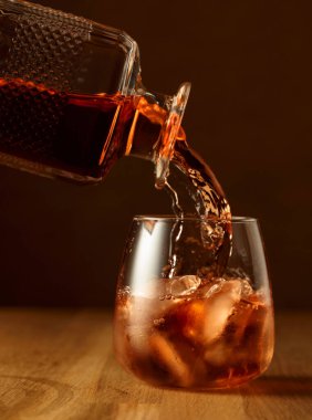 Viski bardağa doğal buzla doldurulur. Meşe ağacının üstünde bir bardak viski..