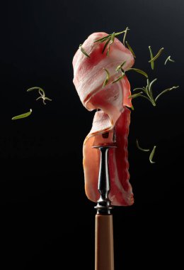 Pastırma ve biberiye. Çatalda tütsülenmiş pastırma ve düşen biberiye yaprakları..