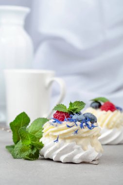 Ahududu, yaban mersini ve gri bir masada naneli Pavlova tatlısı..