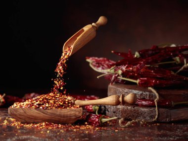 Biberler ahşap bir tabağa dökülür. Kahverengi arka planda kırmızı biber ve kırmızı biber..