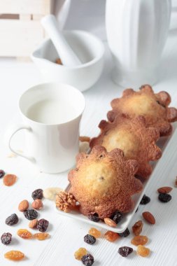 Mutfak masasında sütü olan paskalya çörekleri. Beyaz ahşap bir masada ev yapımı üzümlü kek.. 