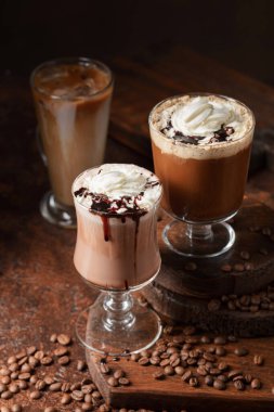 Kahverengi arka planda kremalı kahve ve çikolata içecekler..