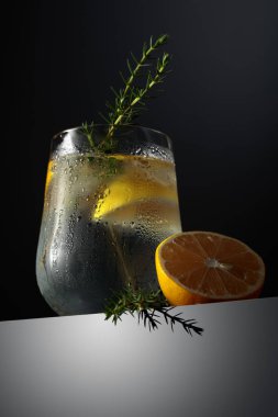 Limonlu cin tonik kokteyli, ardıç dalı, ve koyu yansıtıcı arka planda buz, kopyalama alanı.