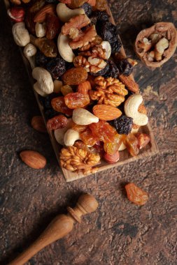 Kahverengi bir arka planda fındık ve kuru üzüm karışımı. Sunulan kuru üzüm, ceviz, fındık, fındık, ceviz, ceviz ve badem. Üst görünüm.