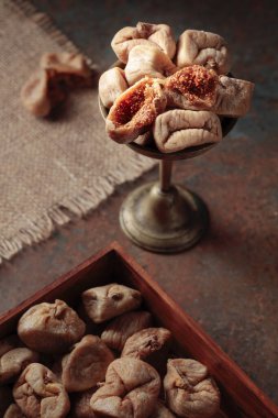 Paslı bir arka planda eski bir pirinç kapta kurutulmuş incir..