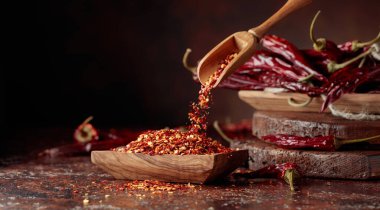 Biberler ahşap bir tabağa dökülür. Kahverengi arka planda kırmızı biber ve kırmızı biber..