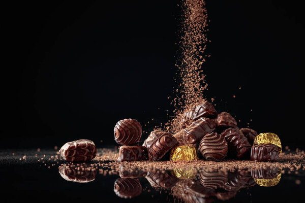 Шоколадные конфеты на черном фоне, посыпанные шоколадной крошкой. Копирование пространства.