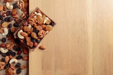 Kurutulmuş meyve ve fındık. Tahta bir masada fındık ve kuru üzüm karışımı. Kopyalama alanı olan üst görünüm.