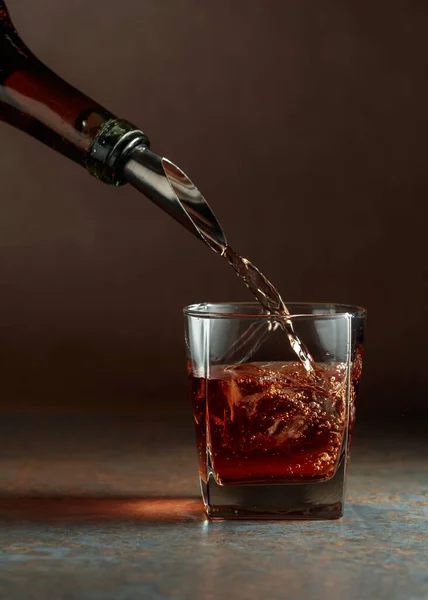 ウィスキーを瓶から氷を入れたフローズングラスに注ぐ 錆びた背景 — ストック写真