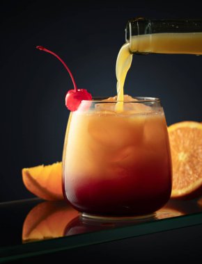 Karanlık bir arka planda tekila Sunrise alkollü kokteyli. Portakal suyu bardağa doldurulur. Tekila, nar suyu ve buz ile..