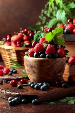 Yapraklı taze böğürtlen. Eski bir masada çilek, ahududu, yabanmersini ve tatlı kirazlar.. 