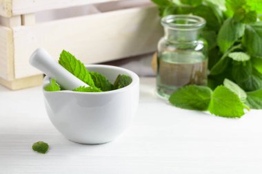 Taze nane yaprakları ve içinde nane yağı bulunan küçük bir şişe. Aromaterapi, spa ve bitkisel ilaç malzemeleri..