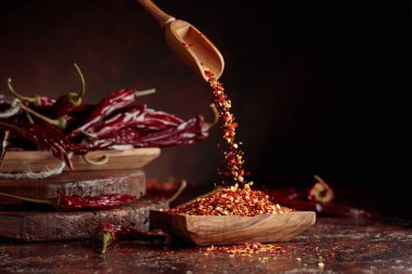 Biberler ahşap bir tabağa dökülür. Kahverengi arka planda kırmızı biber ve kırmızı biber..