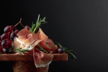 Ahşap bir masada üzümlü ve biberiyeli jambon. Boşluğu kopyala.