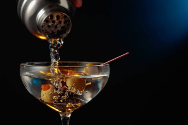 Yeşil zeytinli martini. Kokteyl bardaktan bardağa dökülüyor..