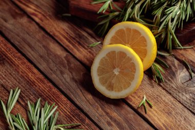 Eski ahşap bir masada biberiye ve limon dilimleri. Boşluğu kopyala.