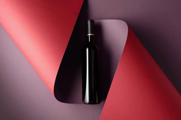 Bottle of red wine on a paper background. Copy space for your text, top view.