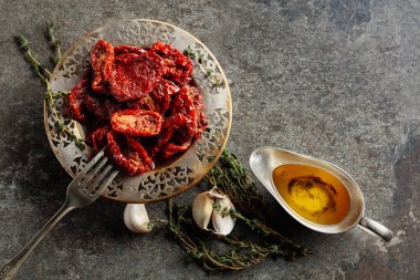 Zeytin yağında kurutulmuş domates kekik ve sarımsak eski bir taş masanın üzerinde. Üst görünüm.