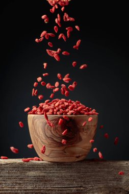 Kurutulmuş goji üzümleri ahşap bir kaseye dökülür. Boşluğu kopyala.