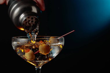 Yeşil zeytinli martini. Kokteyl bardaktan bardağa dökülüyor..