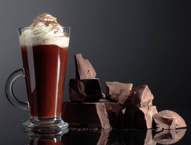 Krem şantili sıcak çikolata ve koyu arkaplanda siyah çikolata parçaları.. 