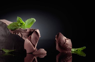 Siyah yansıtıcı arka planda naneli koyu acı çikolata. Boşluğu kopyala.