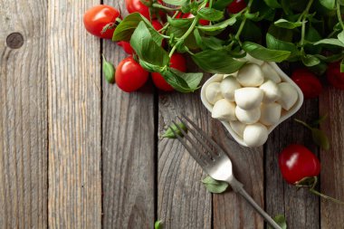 Eski ahşap bir masada fesleğenli ve domatesli Mozzarella peyniri. Geleneksel İtalyan yemeği. Boşluğu kopyala.