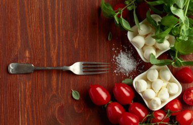 Eski ahşap bir masada fesleğenli ve domatesli Mozzarella peyniri. Geleneksel İtalyan atıştırması.