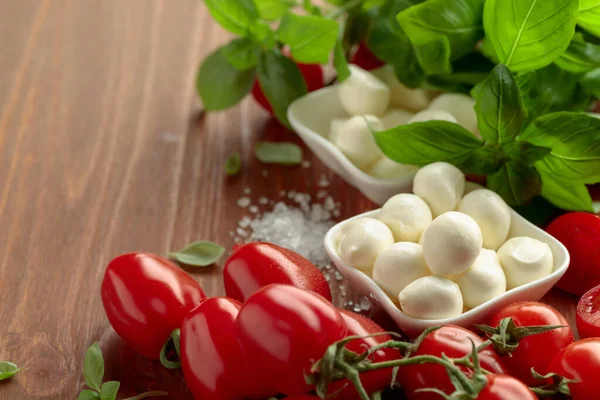 Eski ahşap bir masada fesleğenli ve domatesli Mozzarella peyniri. Geleneksel İtalyan atıştırması.