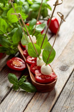 Eski ahşap bir masada fesleğenli ve domatesli Mozzarella. Geleneksel İtalyan atıştırması.