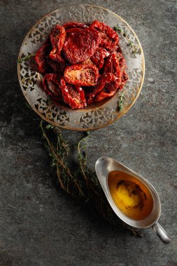 Zeytinyağında güneşte kurutulmuş domatesler ve eski bir taş masanın üzerinde kekik. Üst görünüm.