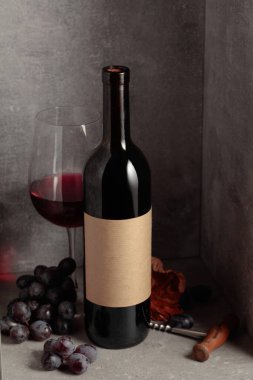 Mavi üzümlü bir şişe ve bir bardak kırmızı şarap. Şişede eski boş etiket var. Boşluğu kopyala.