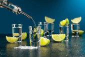Tequila se nalije do sklenice. Panáky tequily s plátky vápna a mořskou solí.
