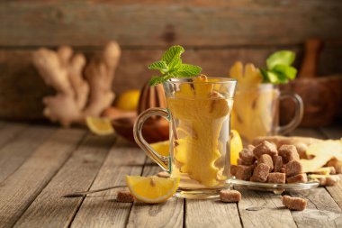 Malzemeli zencefil çayı. Zencefil, limon, nane ve esmer şeker eski ahşap bir masada.