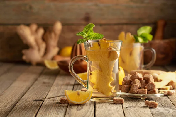 Malzemeli zencefil çayı. Zencefil, limon, nane ve esmer şeker eski ahşap bir masada.