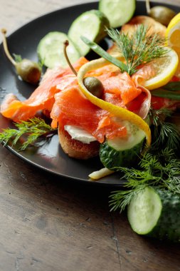 Somonlu sandviç, krem peynir, dereotu, salatalık, kapari, yeşil soğan ve limon..