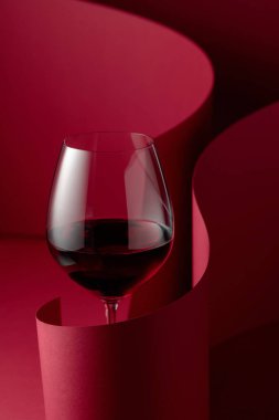 Kırmızı arka planda bir kadeh kırmızı şarap..