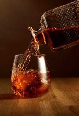 Viski bardağa doğal buzla doldurulur. Meşe ağacının üstünde bir bardak viski..