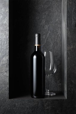 Siyah taştan bir arka planda bir şişe kırmızı şarap. Boşluğu kopyala.