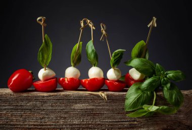 Eski bir tahta üzerinde fesleğen ve domatesli Mozzarella. Geleneksel İtalyan atıştırması.