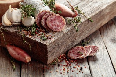 Geleneksel kuru sosis kekik, sarımsak, soğan ve baharatlı. Eski ahşap bir masada kurutulmuş sosis..