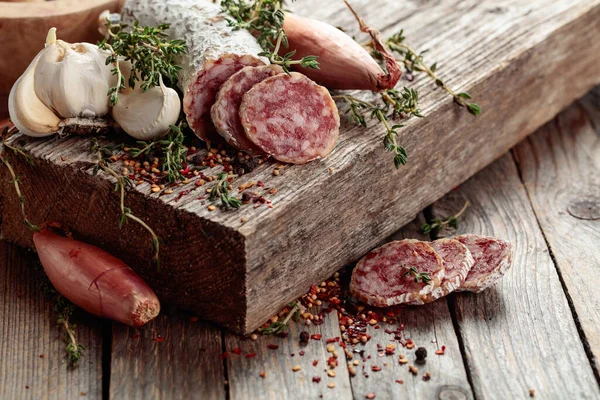 Geleneksel kuru sosis kekik, sarımsak, soğan ve baharatlı. Eski ahşap bir masada kurutulmuş sosis..