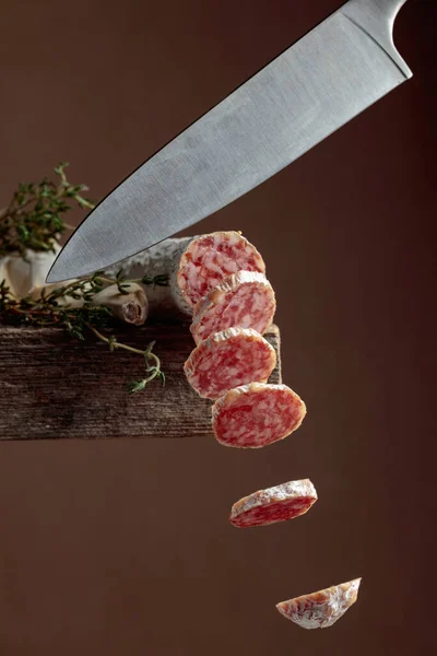 Traditional dry-cured sausage with thyme and garlic. Slices of flying dry-cured sausage in motion. Copy space.